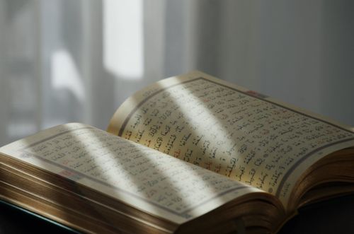 Free An open Quran with Arabic text, bathed in soft sunlight, symbolizing peace and spirituality. Stock Photo