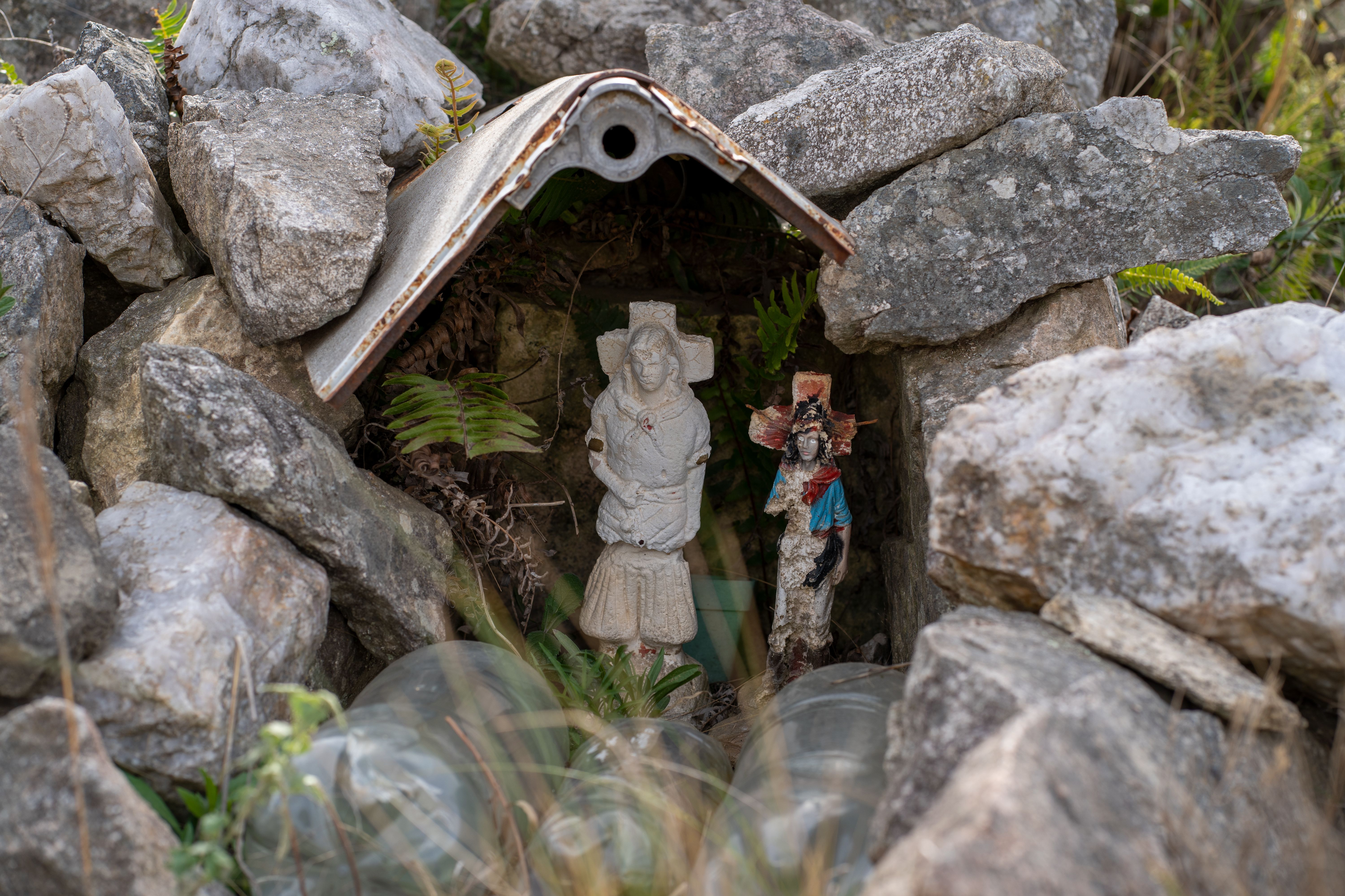 A simple stone shrine surrounded by vegetation in a rural setting, typical of religious sites in Uganda.