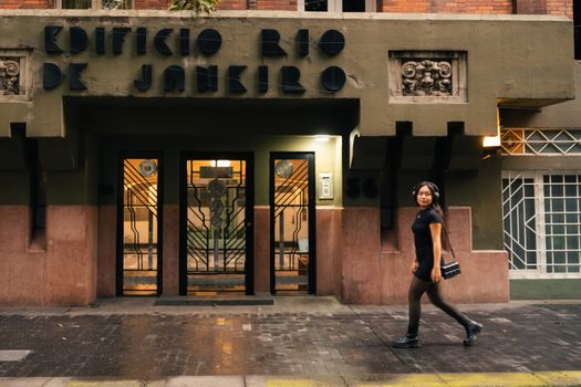 A woman strides past Edificio Rio de Janeiro, showcasing urban architecture.