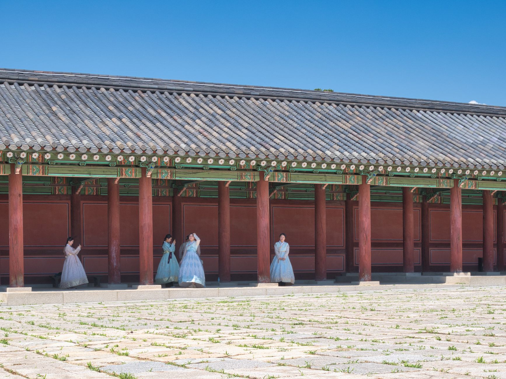 Women in traditional Korean hanbok stand by a historical palace in Seoul, showcasing cultural heritage.