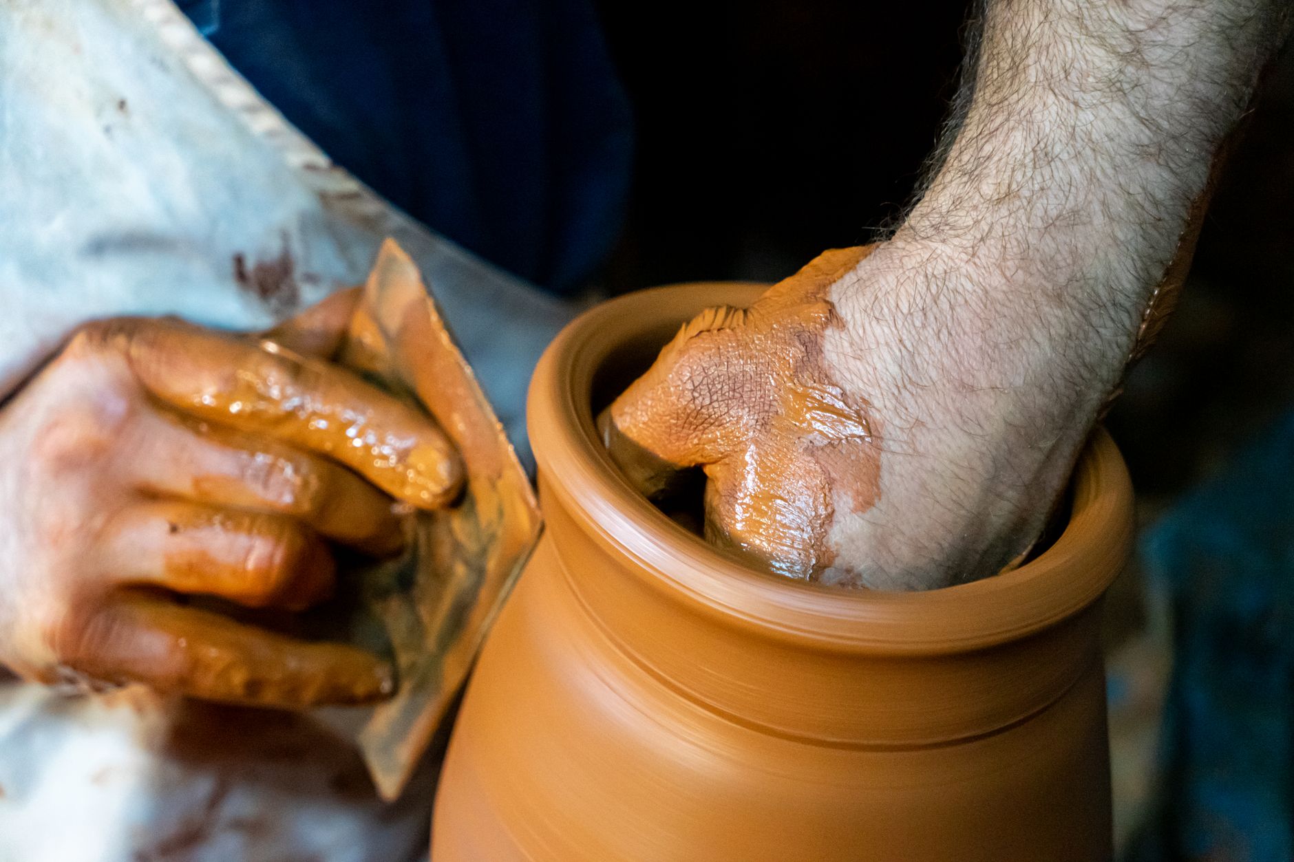 Artisan's hands shaping a clay pot on a pottery wheel, capturing craftsmanship and creativity.