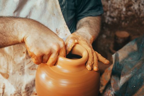 Free Artisan craft person shaping a clay pot on a spinning pottery wheel with expertise. Stock Photo