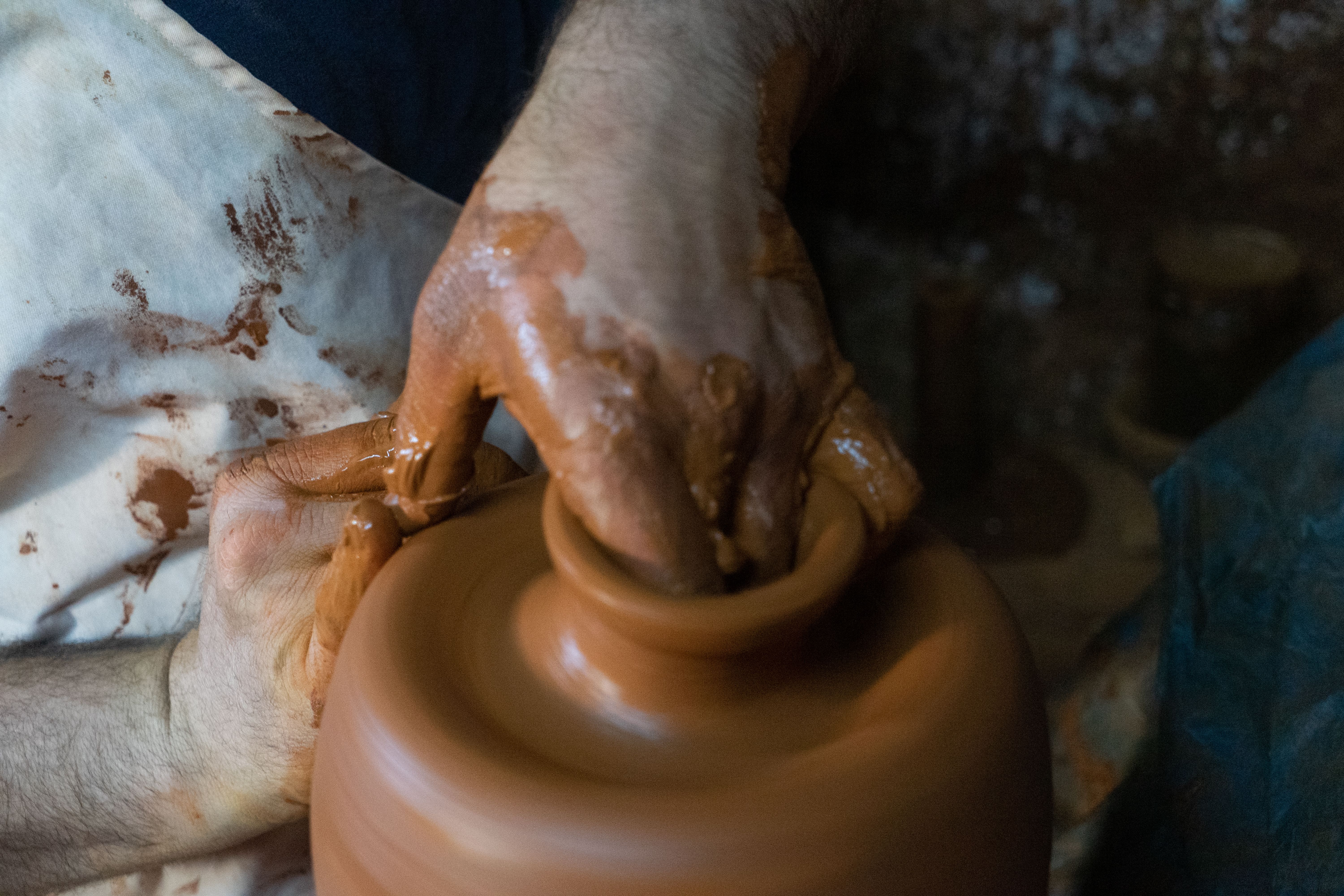 Hands shaping clay on pottery wheel