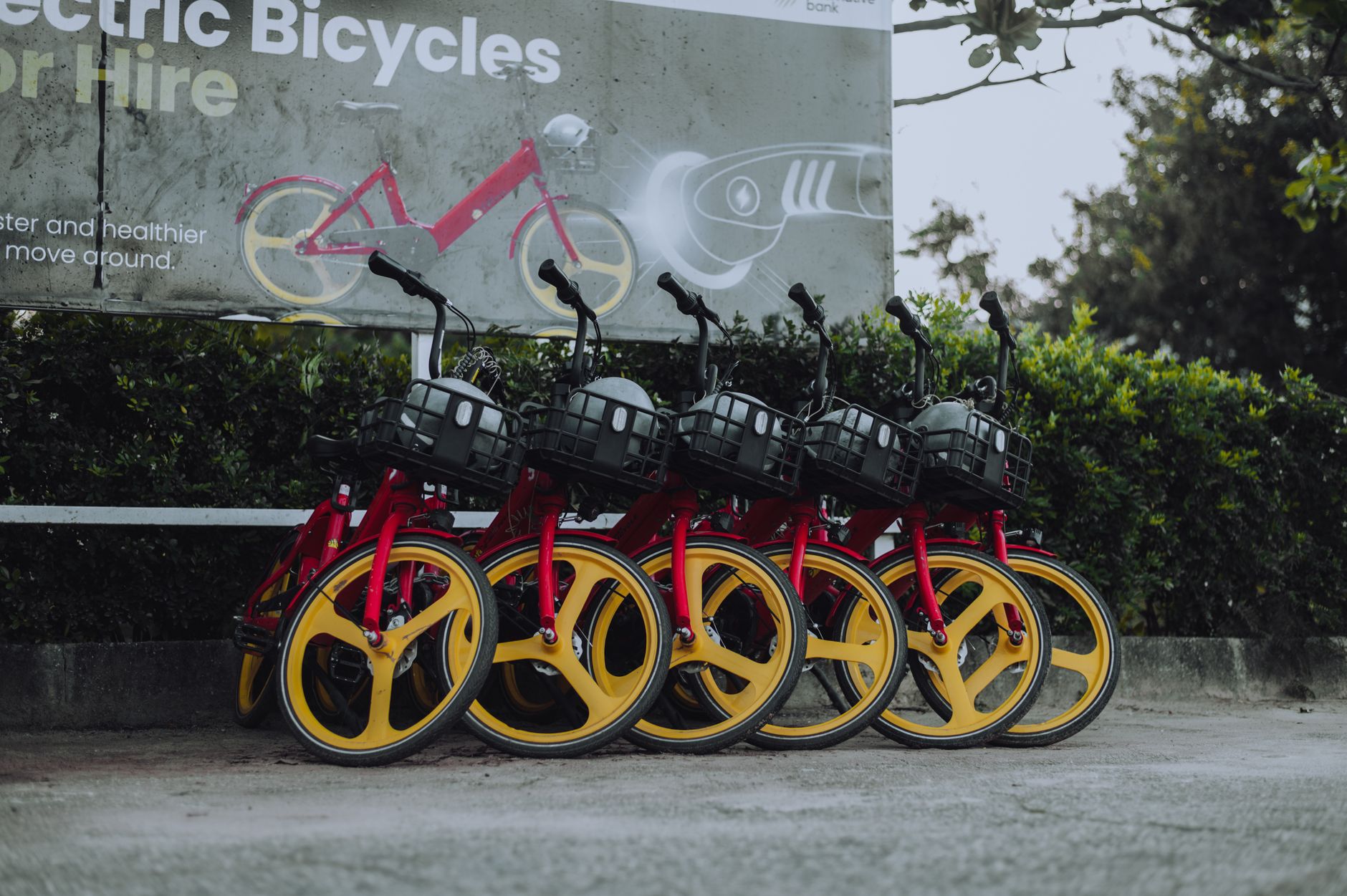 Vibrant red and yellow electric bicycles parked outside, promoting eco-friendly transport.