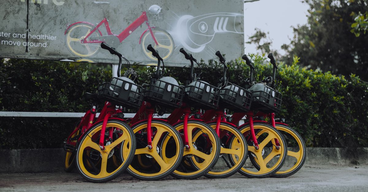 Photo by Deji Prince Vibrant red and yellow electric bicycles parked outside, promoting eco-friendly transport.