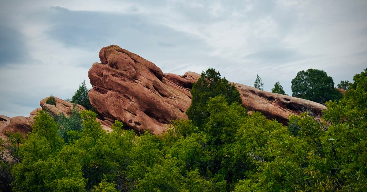 Stunning red sandstone rock formations amidst lush green foliage in Colorado.