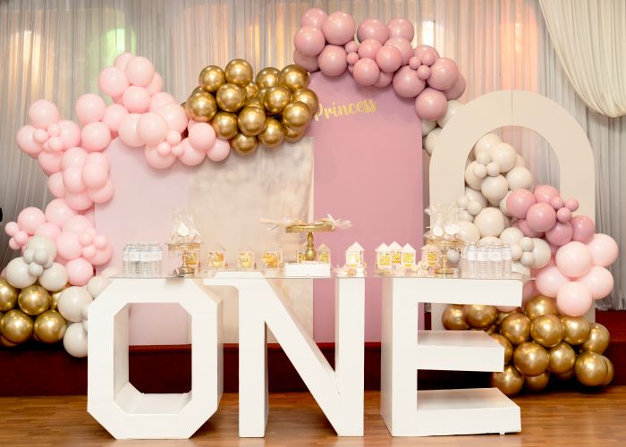 Pink, gold and white balloon backdrop with ONE sign