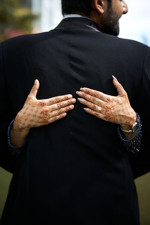 Free Elegant wedding photograph featuring henna decorated hands embracing a groom. Stock Photo