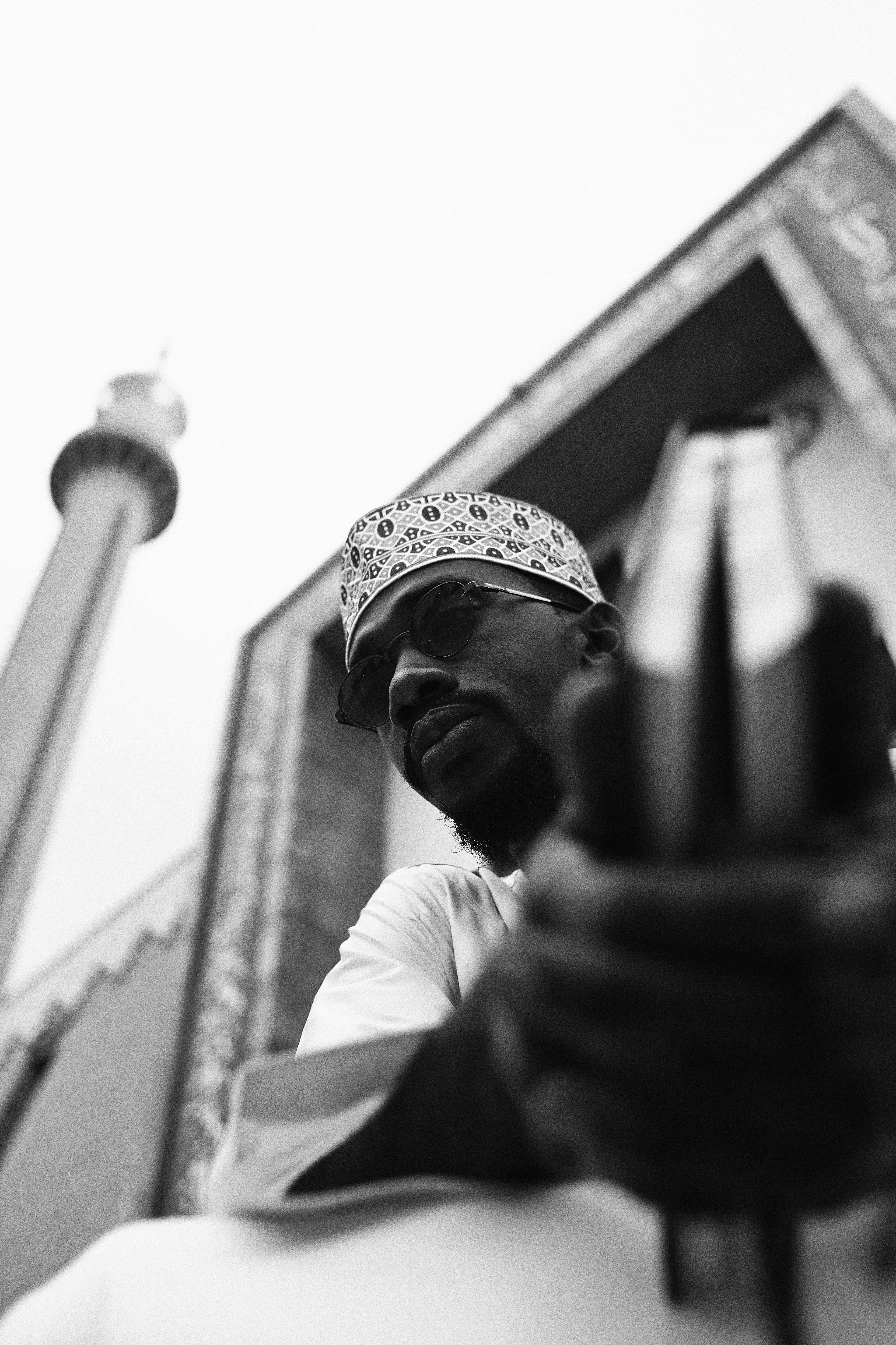 Black and white photo of a man in traditional attire outside an Abuja mosque.