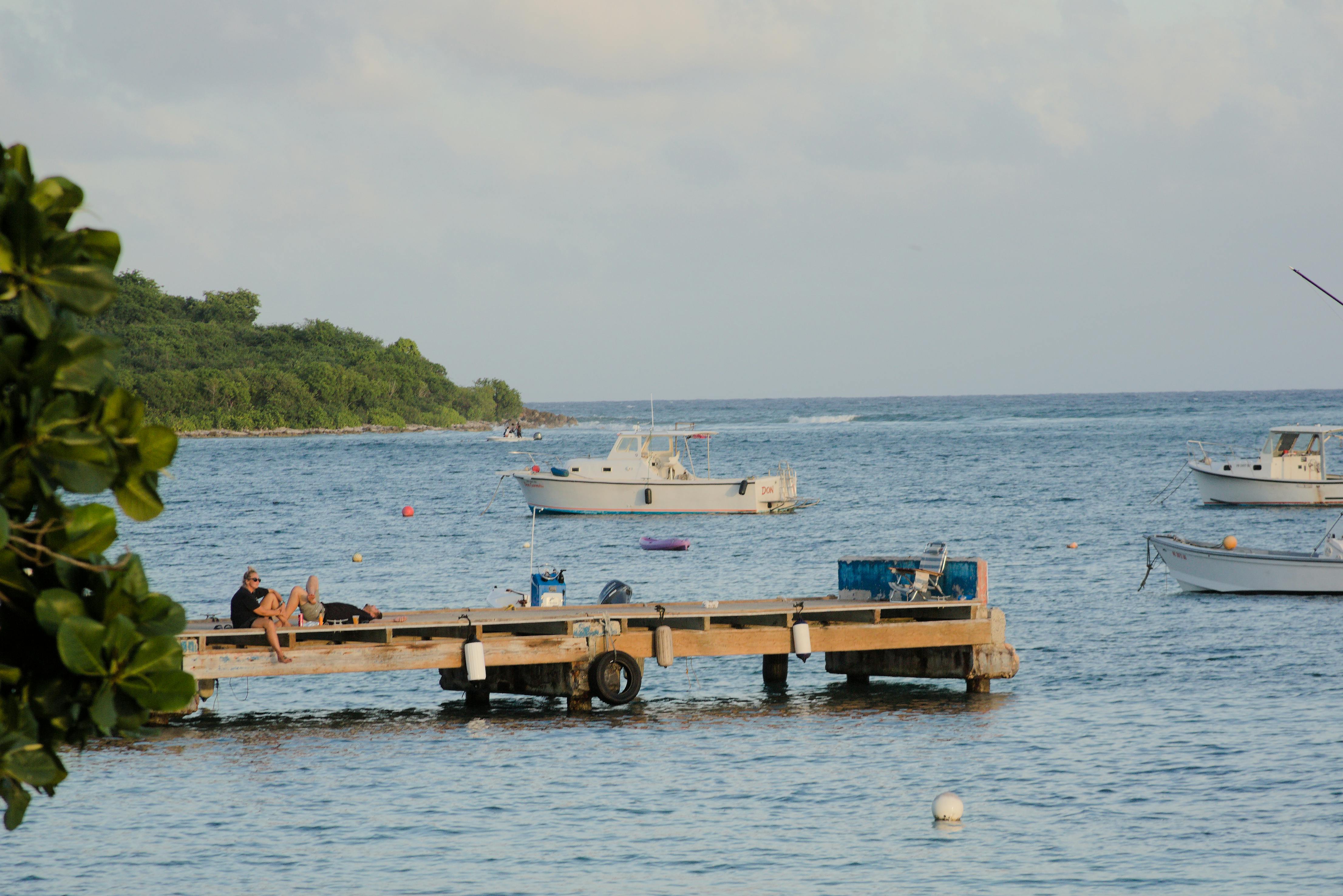 People relaxing on a dock with boats on the serene waters of Vieques, Puerto Rico. - Vieques