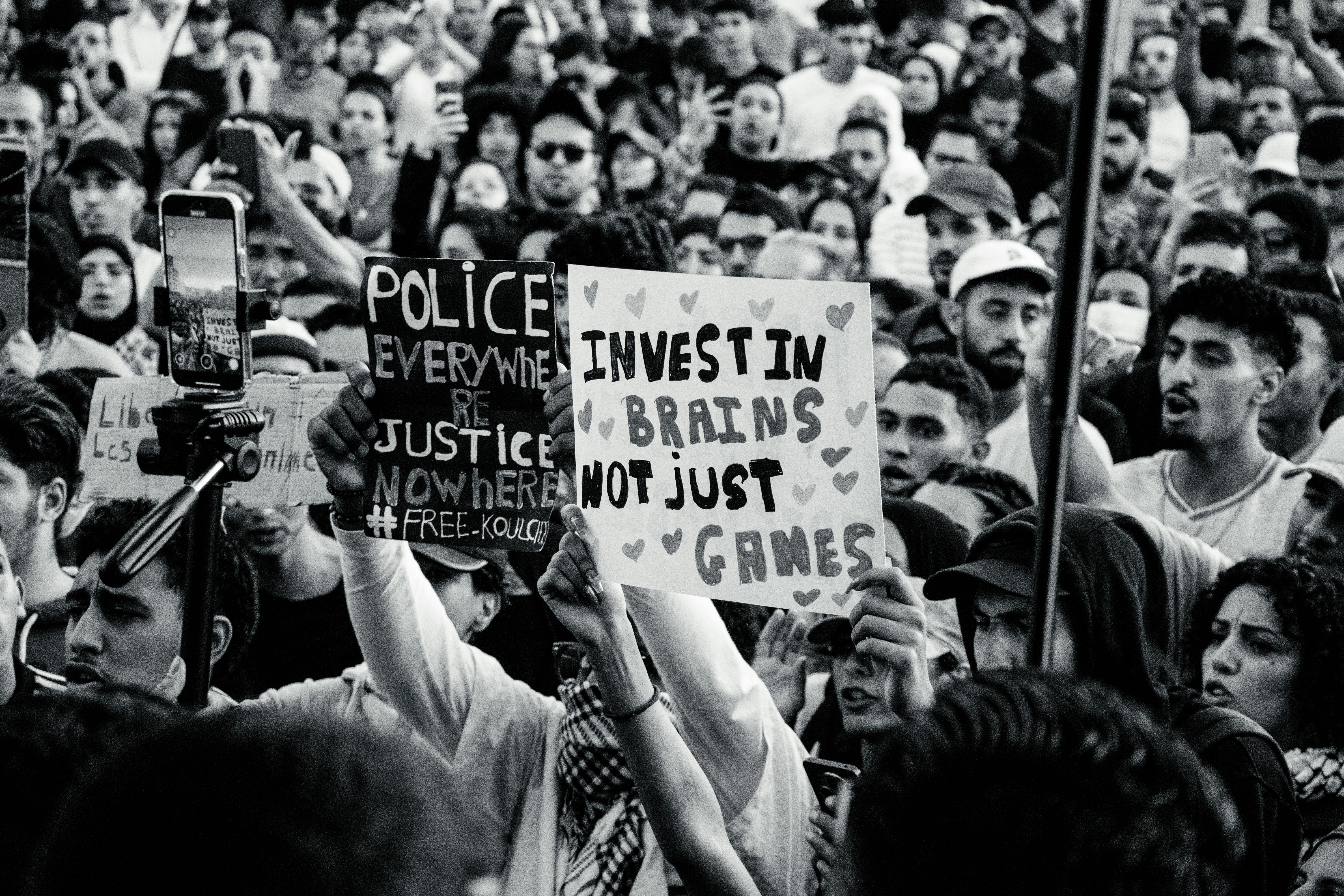 Crowd of young adults protesting with impactful signs in black and white.