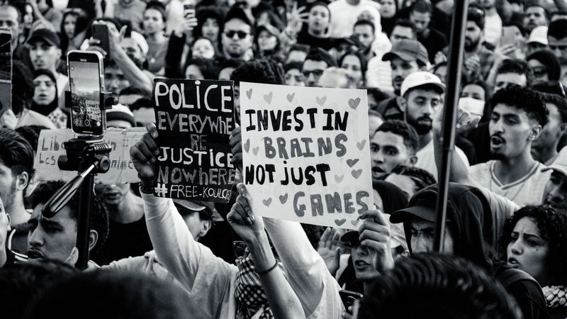 Crowd of young adults protesting with impactful signs in black and white.