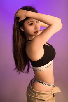 Stylish portrait of a young adult woman posing in vibrant studio lighting.