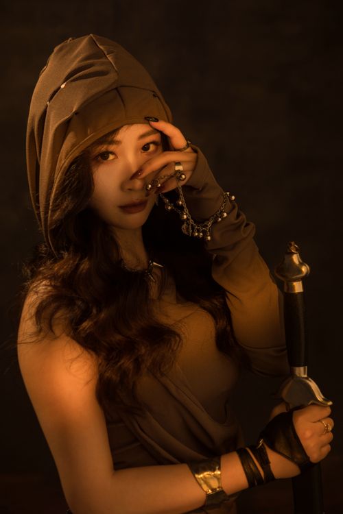 Free Woman in a hood holding a sword, exuding a mysterious, medieval aura. Stock Photo