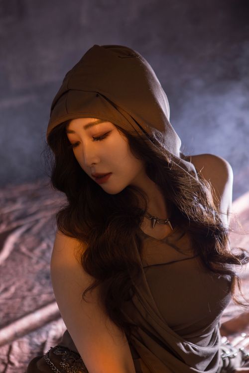 Free Portrait of a stylish woman in a hooded outfit with soft lighting, showcasing elegance and mystery. Stock Photo