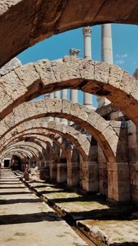 Explore the historic stone arches at Izmir's ancient Agora with clear blue skies above.