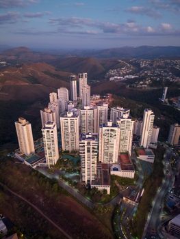 Stunning aerial view of skyscrapers amidst mountains in Belo Horizonte at twilight.
