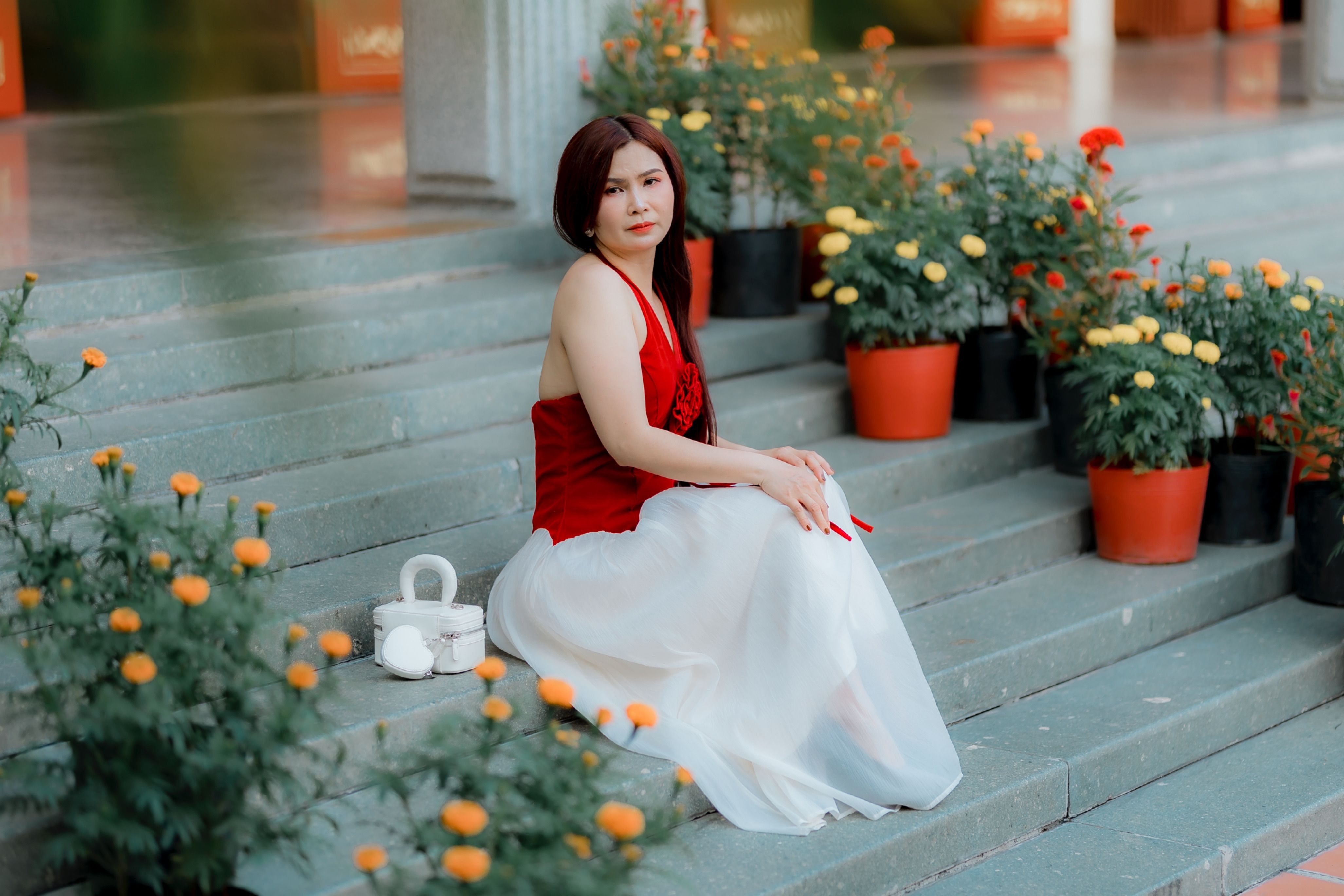 Woman in Red Top Sitting on Stone Steps with Flowers · Free Stock Photo
