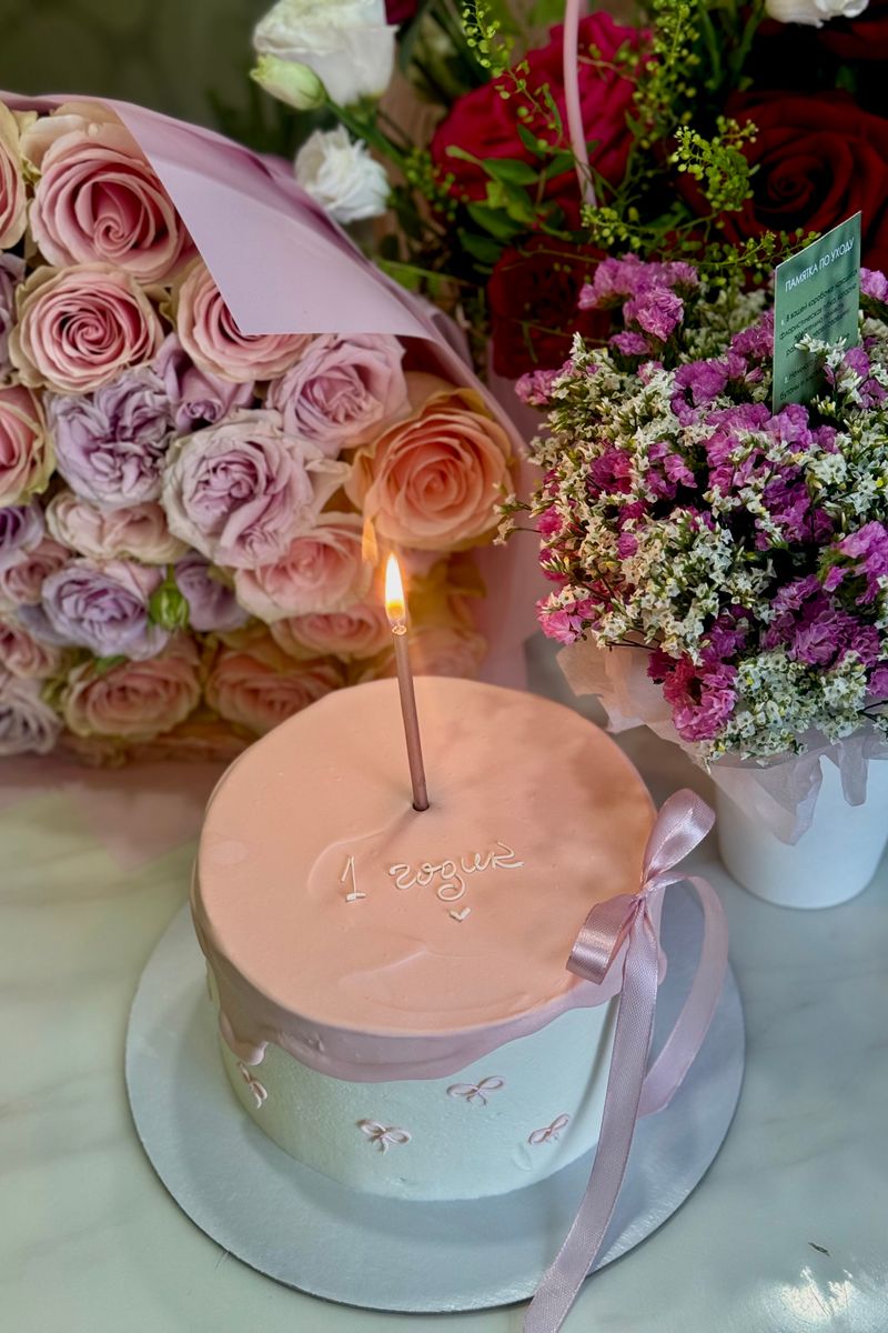 Pink celebration cake topped with fresh roses and carnations