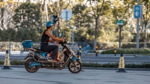 Free Man in blue helmet riding a scooter on a sunny day in the city. Stock Photo