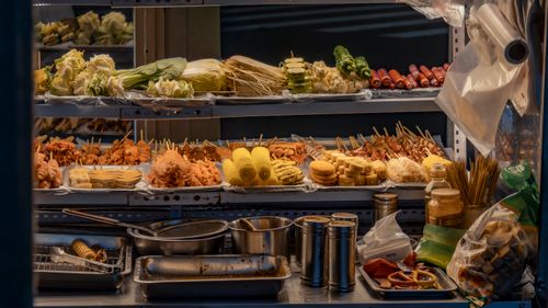 Free Vibrant street food stall with diverse skewers, vegetables, and condiments on display. Stock Photo