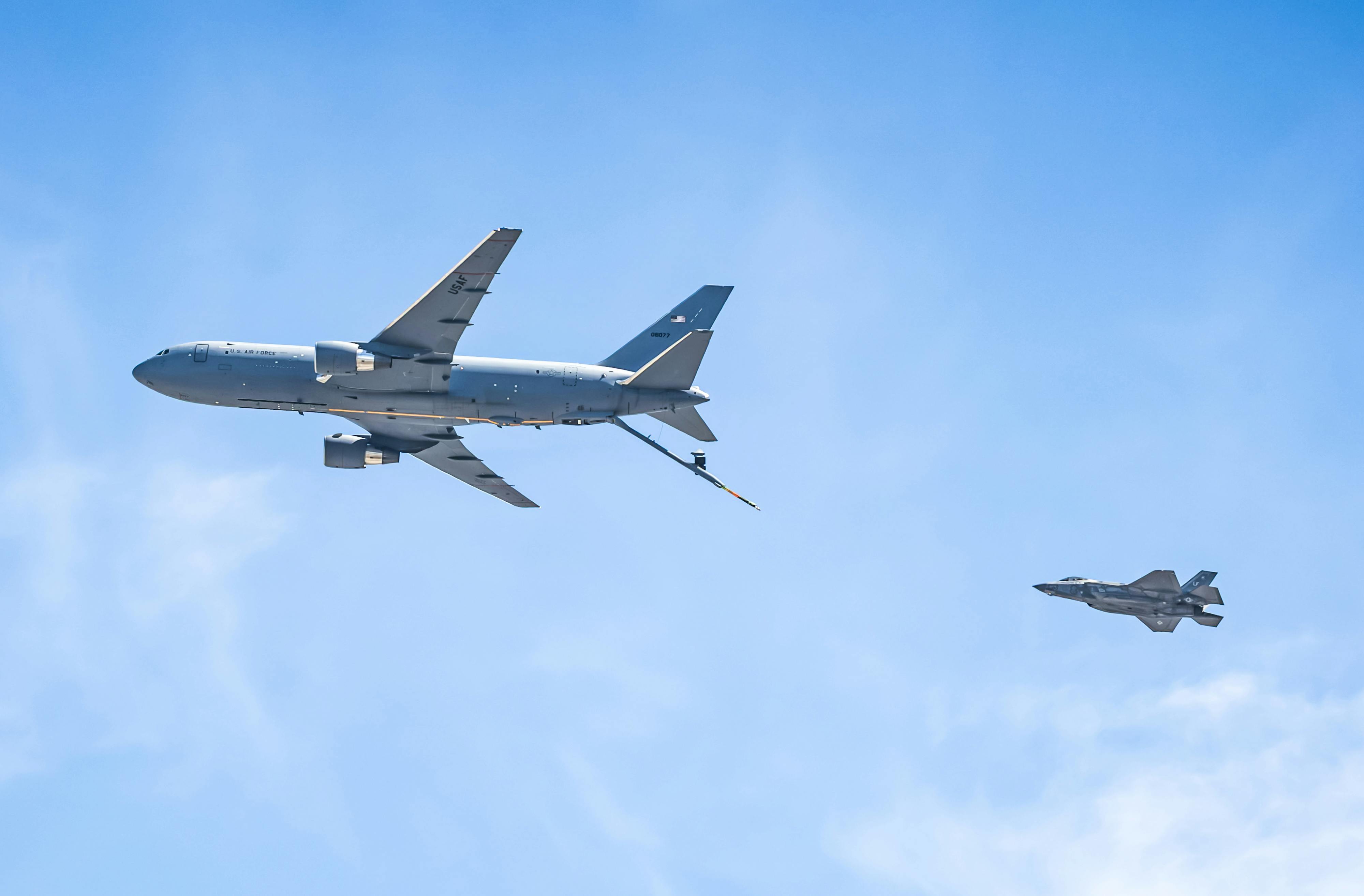 Aerial view of a KC-46 Pegasus and F-35 fighter jet flying in clear skies.