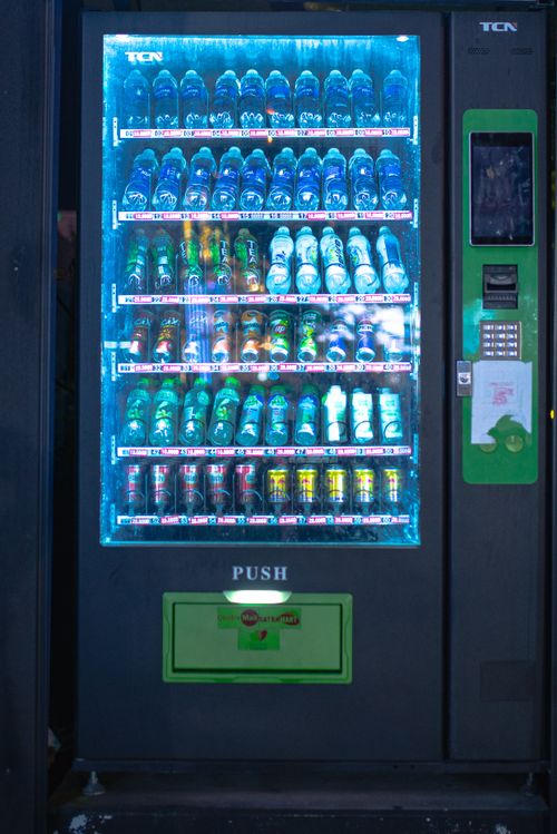 Free A brightly lit vending machine displaying assorted beverages at night, capturing urban convenience. Stock Photo