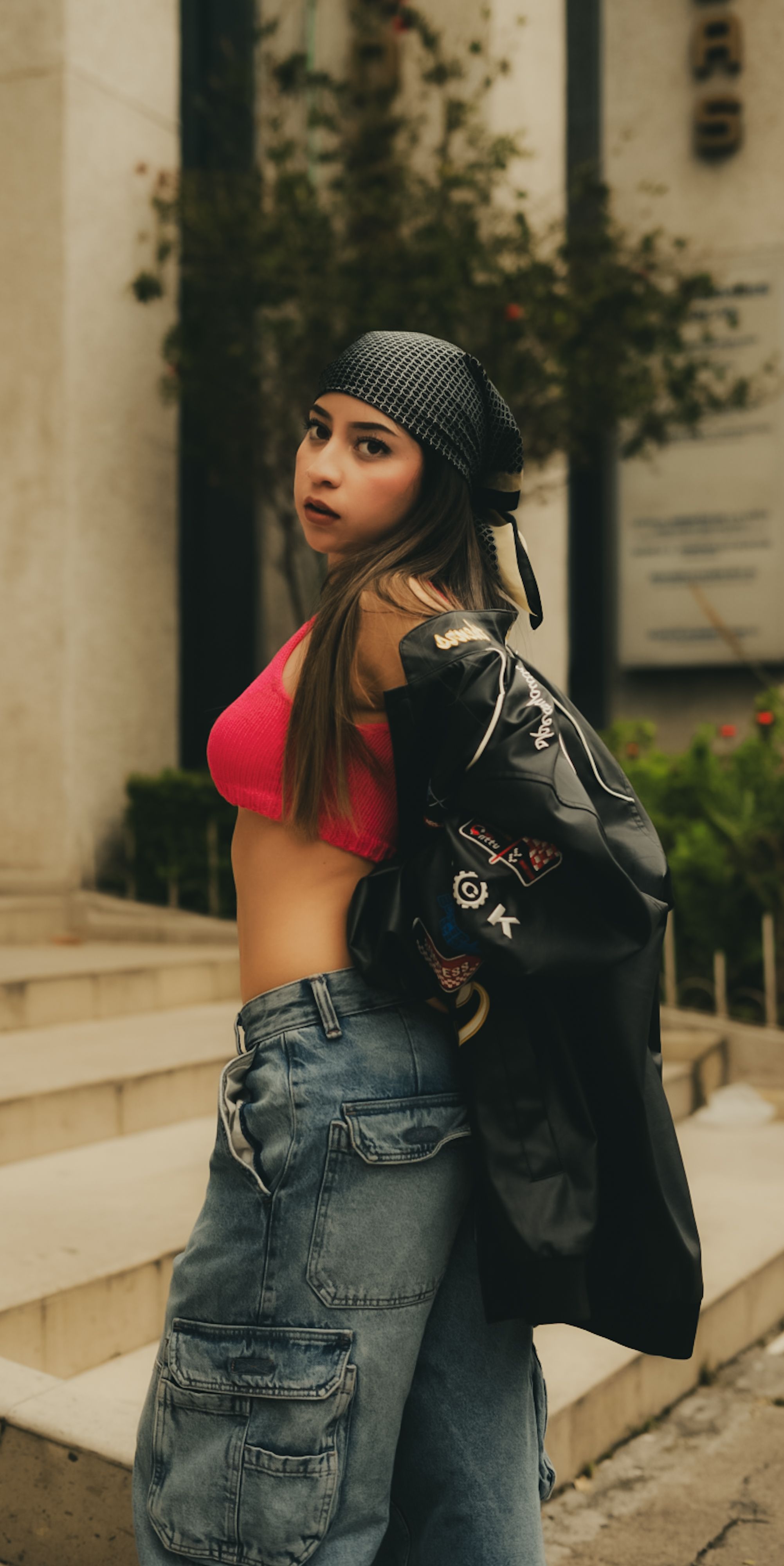 Fashionable young woman in urban streetwear posing outdoors with a confident look.