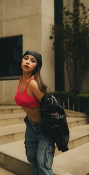 Stylish young woman in vibrant attire posing outdoors on city steps.