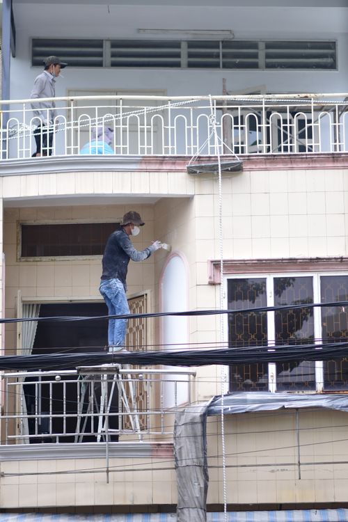 Free Two workers painting a building facade from a scaffold on an urban street. Stock Photo