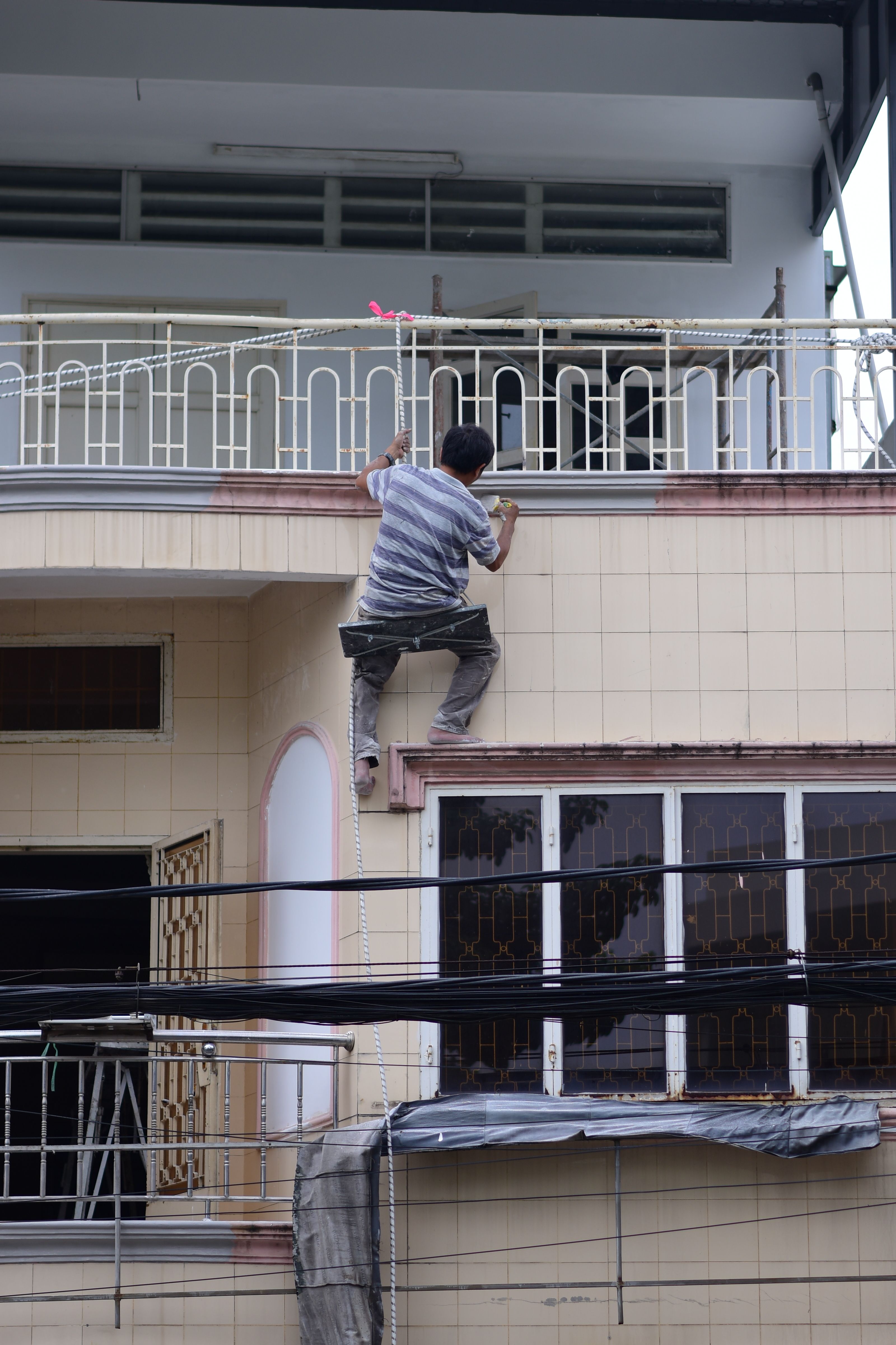 A man scaling the exterior of a building in daylight, showcasing risk and urban exploration.