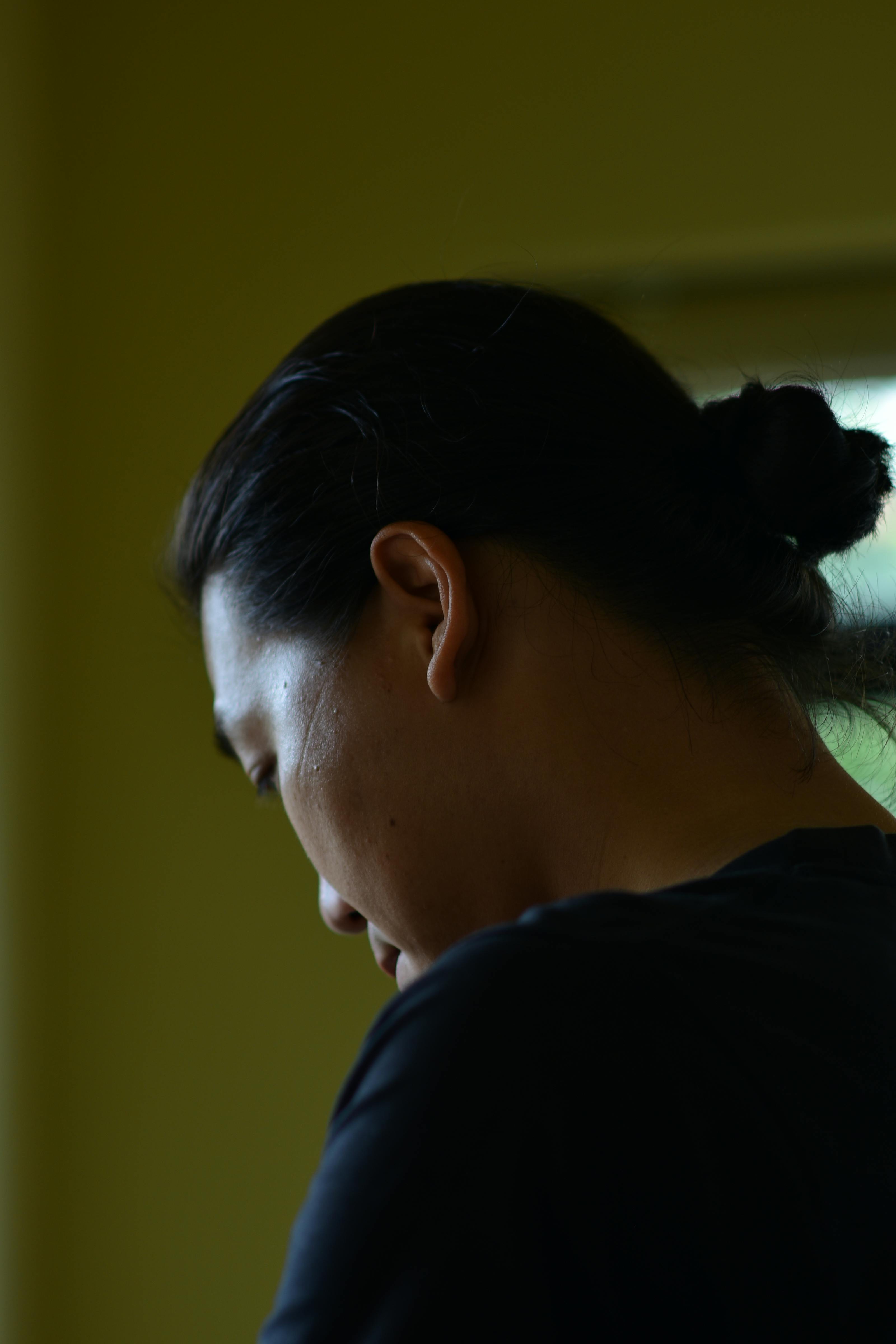 Side profile of a young man indoors with a calm expression, softly lit by daylight.