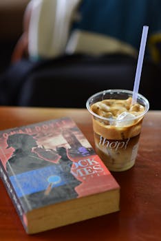 A cup of iced coffee next to a book, creating a cozy reading atmosphere.