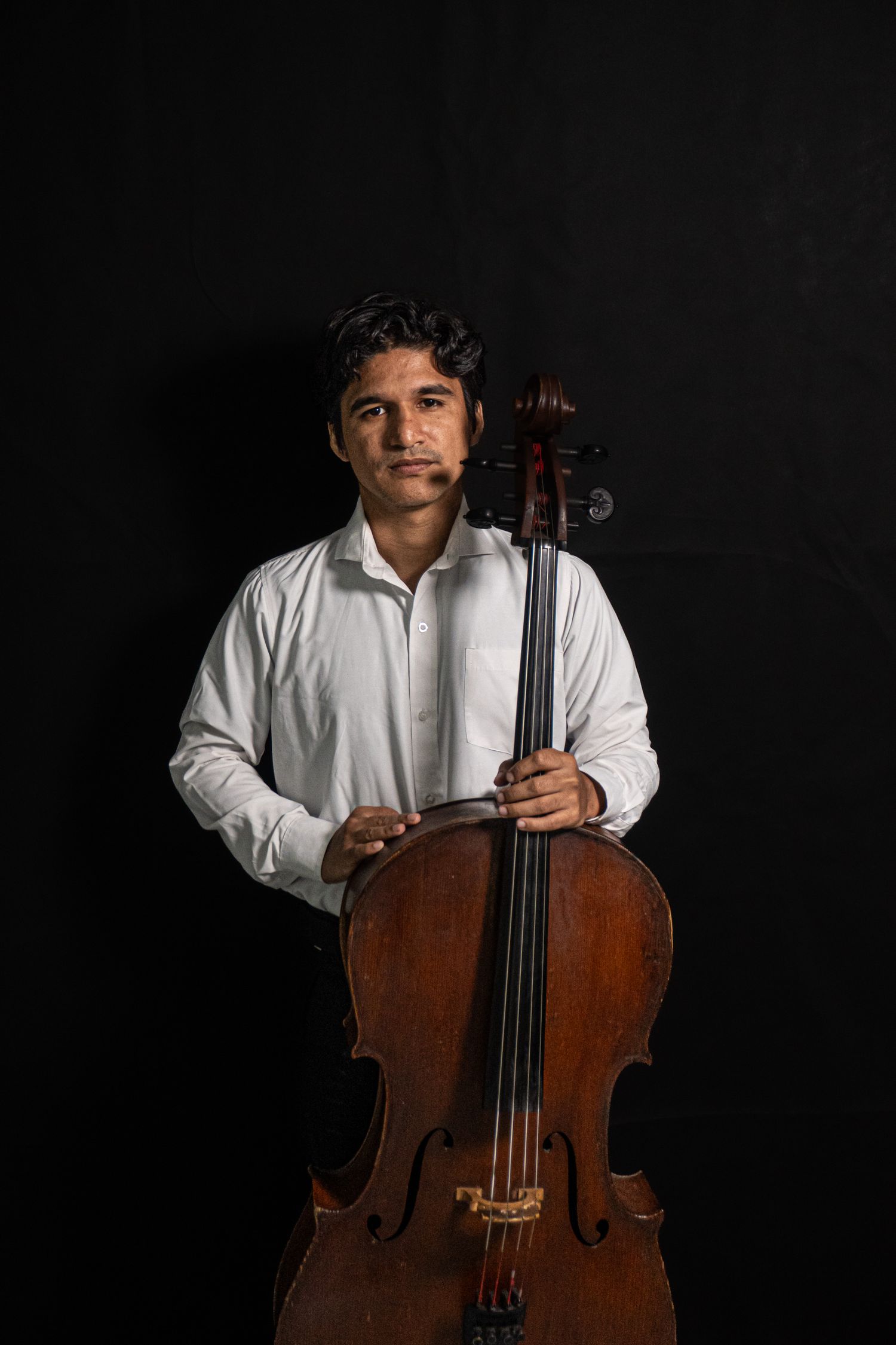 Marshall McDaniel with cello against a dramatic dark background