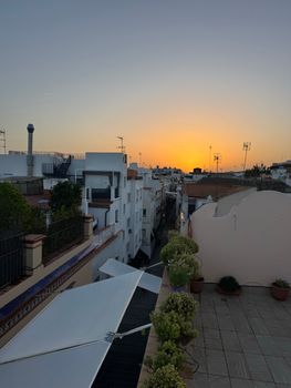 Serene sunset casting golden hues over quaint city rooftops and terraces.