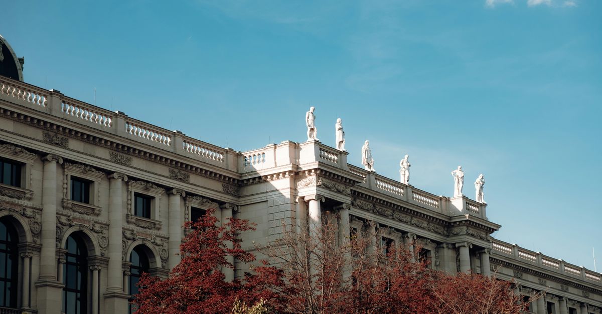 Elegant Vienna architecture with classical statues under a clear blue sky.