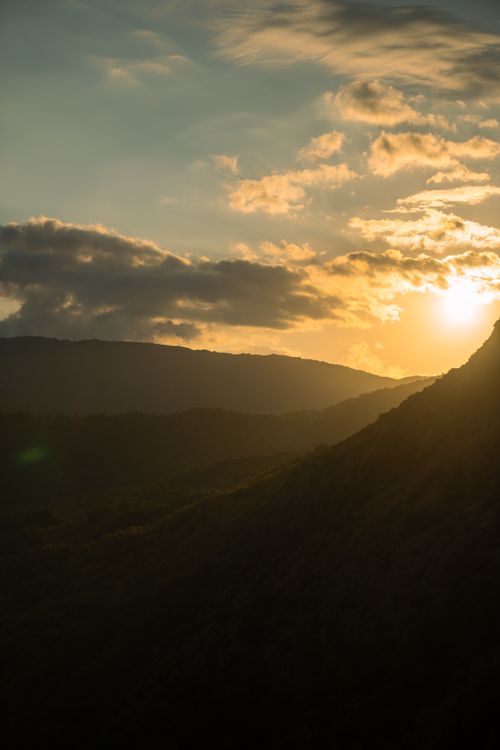 Free Gorgeous sunset over a mountainous landscape with a dramatic sky, capturing the natural beauty and tranquility. Stock Photo