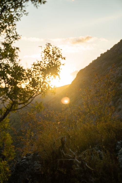 Free Serene sunset view over a mountainous landscape with warm golden hues and lush vegetation. Stock Photo