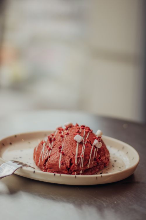 Free Close-up of a freshly baked red velvet cookie with icing on a plate, perfect for dessert inspiration. Stock Photo