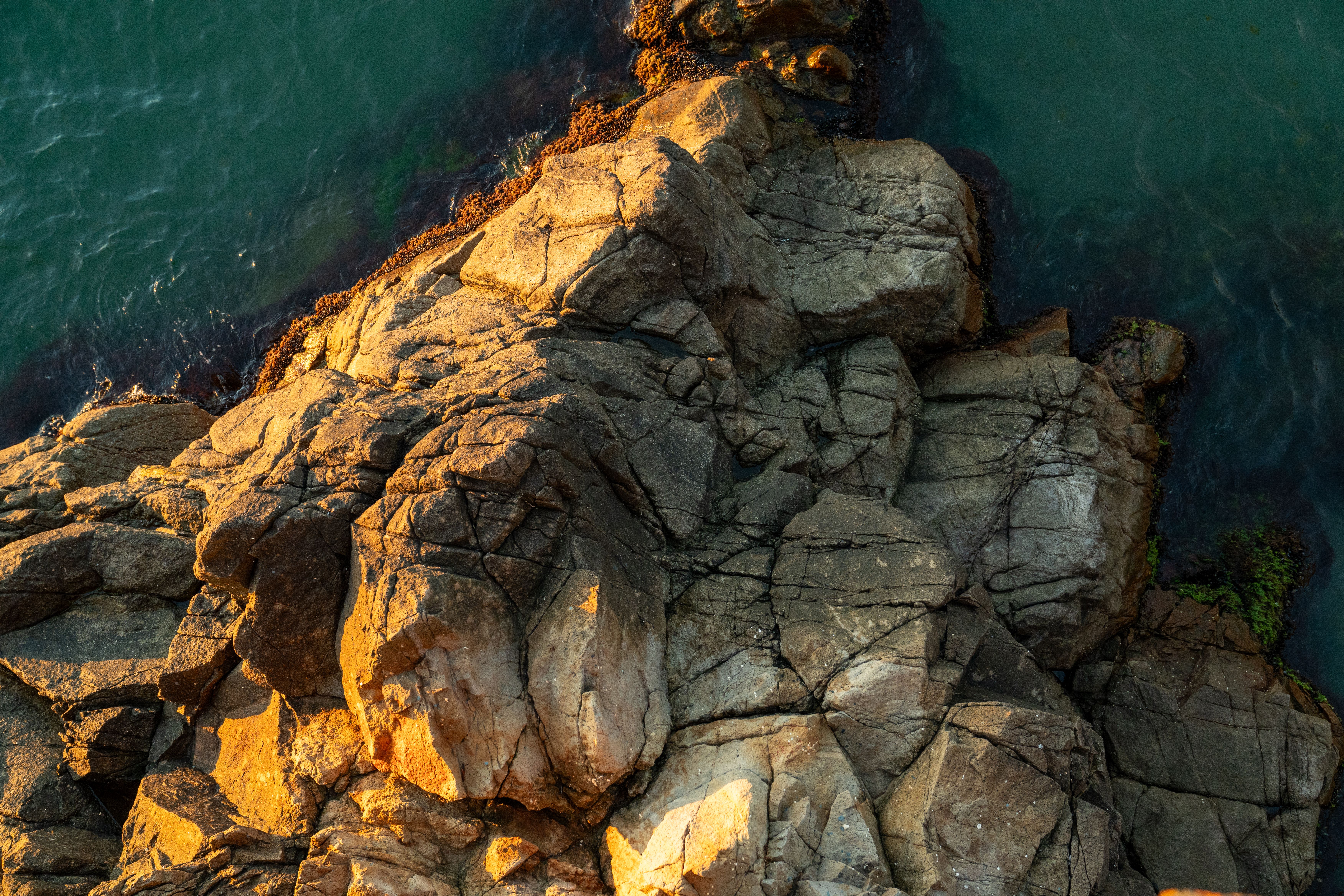 Aerial View of Sunlit Coastal Rock Formation · Free Stock Photo