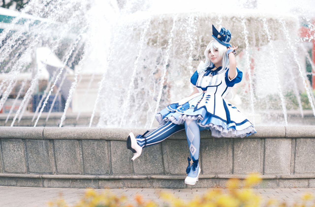 young woman in striking blue and white cosplay outfit poses beside a d
