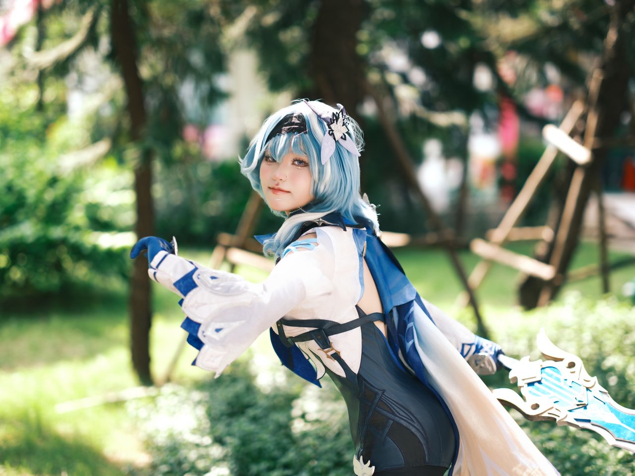 cosplayer with blue hair poses in detailed costume amidst vibrant gree