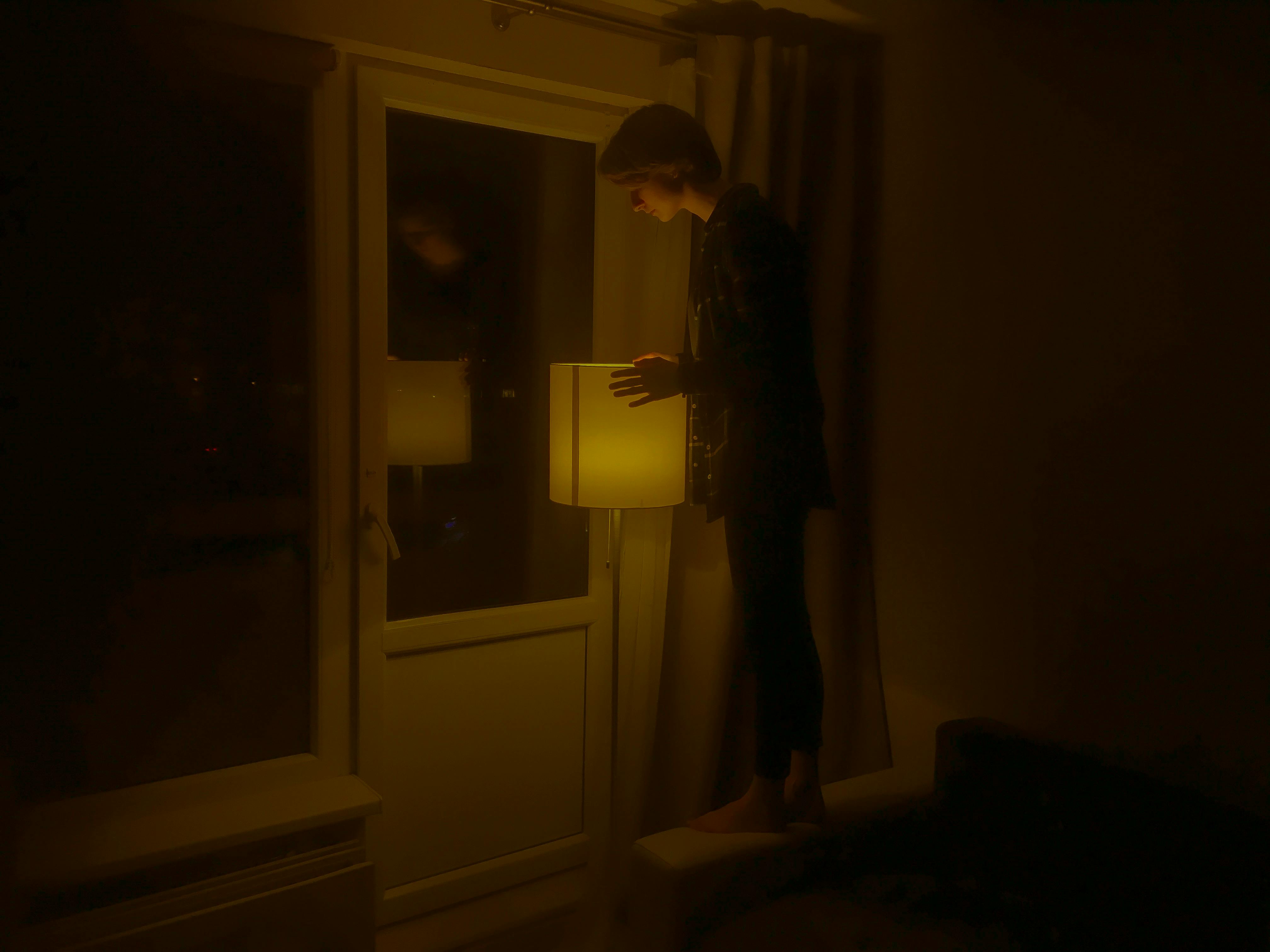 室内昏暗的落地灯前站着一个人，营造出一种喜怒无常的气氛