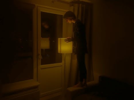 室内昏暗的落地灯前站着一个人，营造出一种喜怒无常的气氛