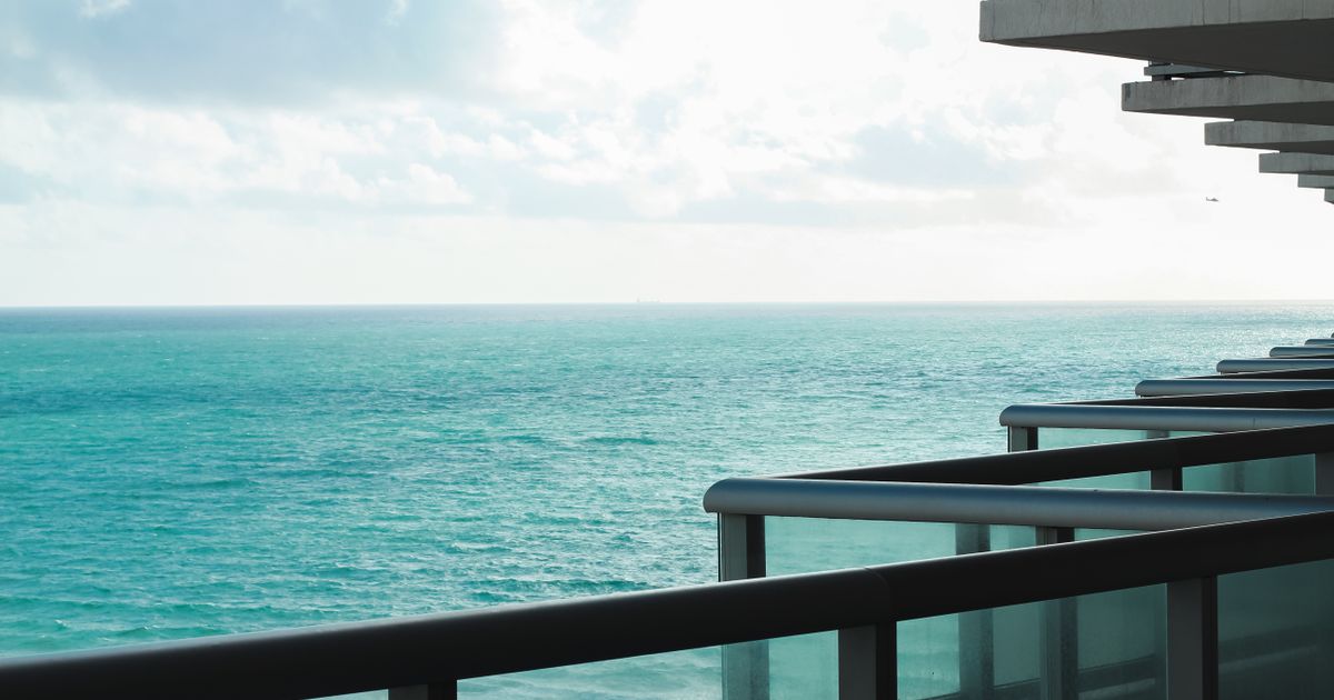 Varanda de apartamento moderno com vista para o mar em um dia ensolarado.