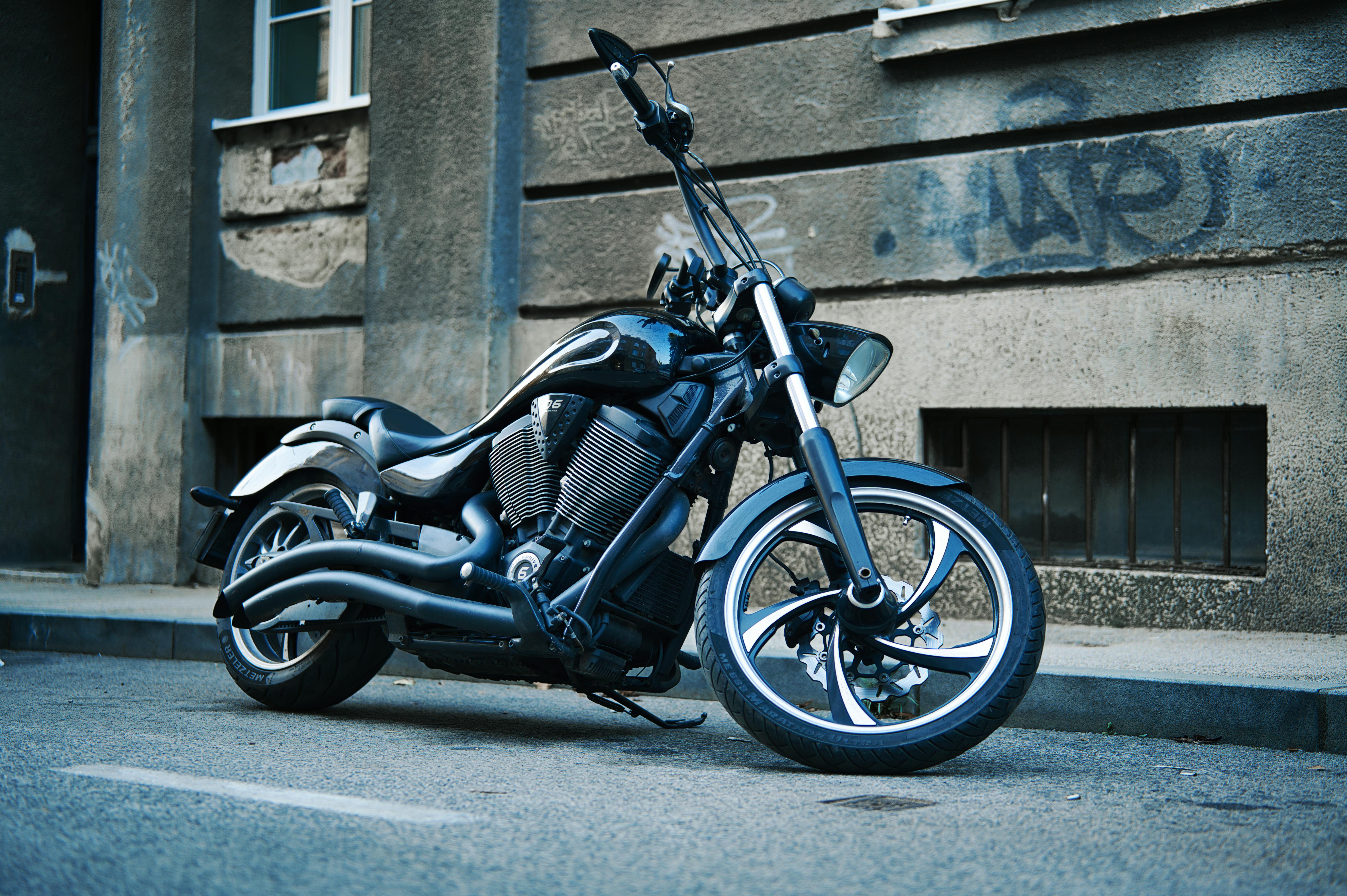 Stylish black motorcycle parked on a graffiti-lined street, epitome of urban style.