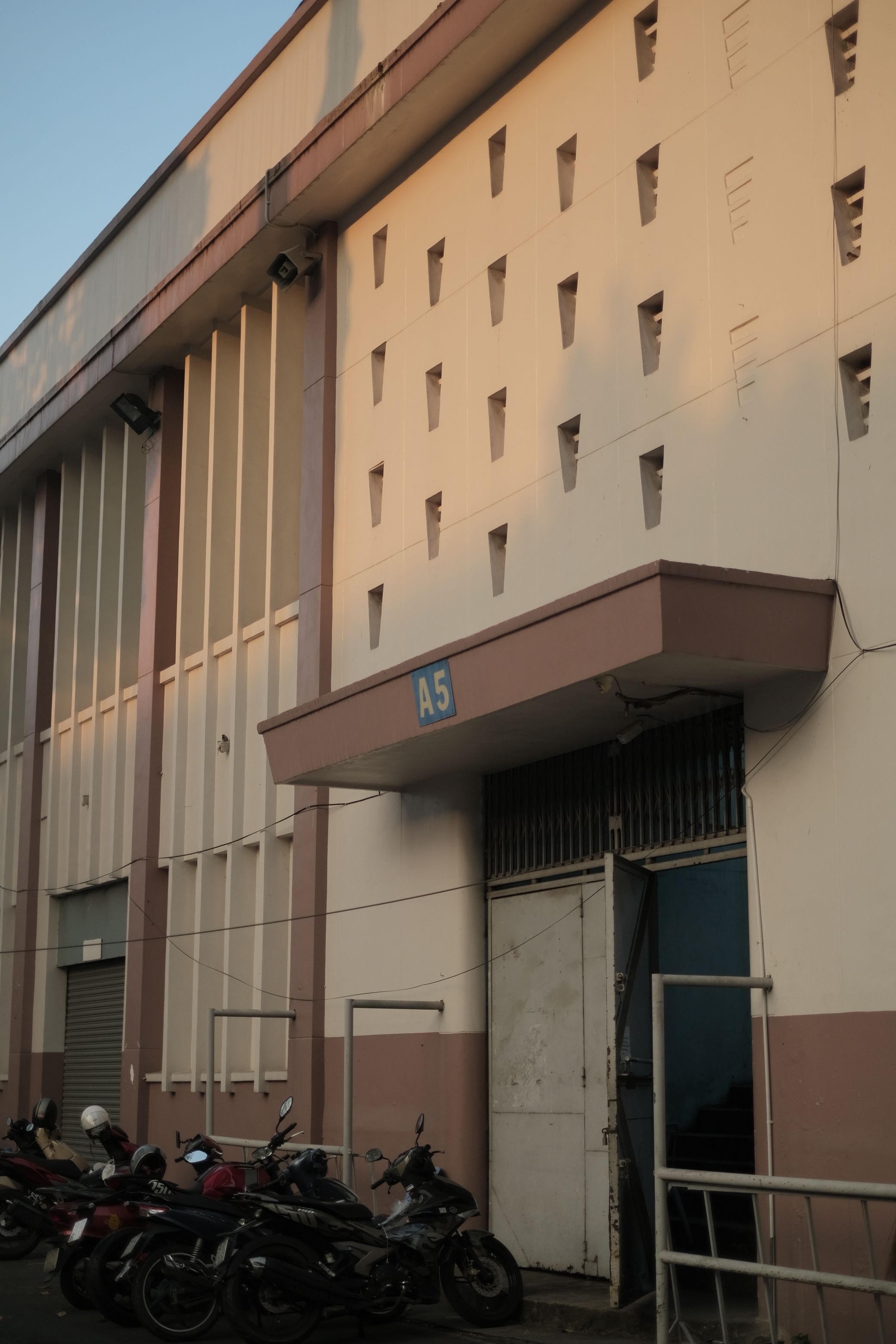 Exterior view of a warehouse door with parked motorcycles, during evening light.