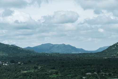 Free Scenic view of lush greenery and mountains under cloudy sky in Bengaluru, India. Stock Photo