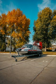 A vibrant hovercraft parked outdoors surrounded by colorful autumn trees. — photo by Daniil Kondrashin