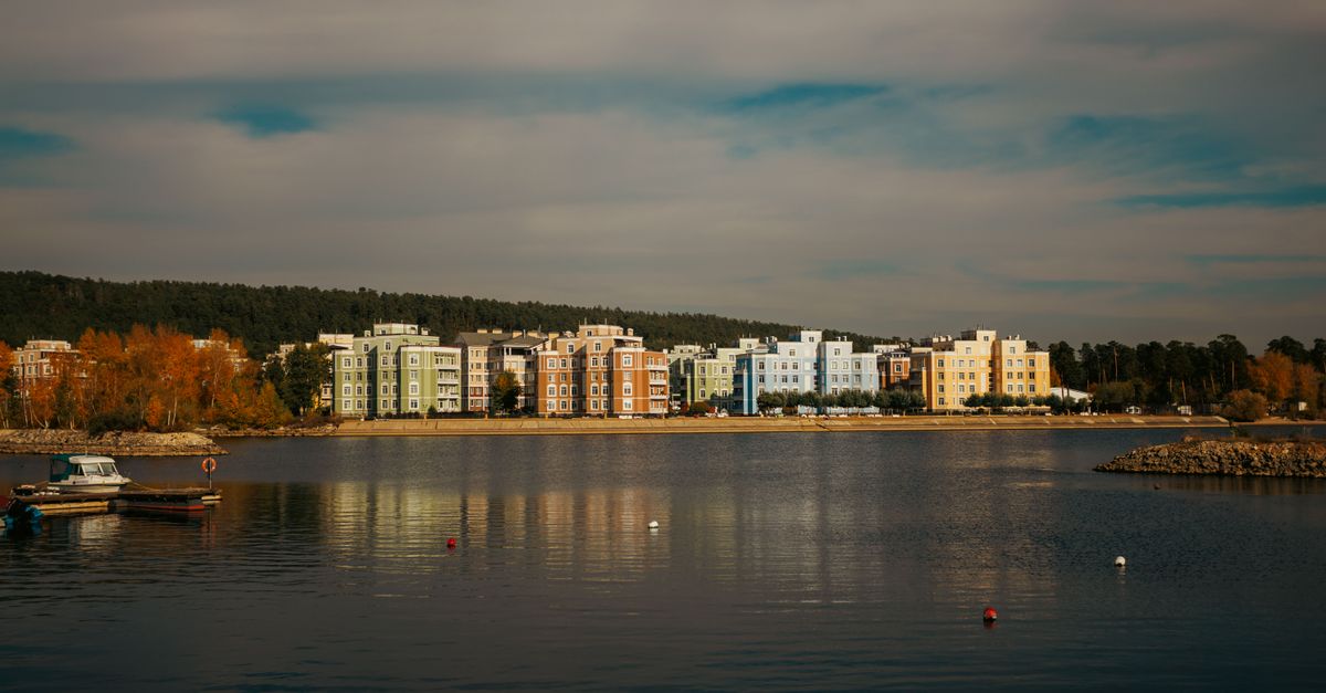 Scenic view of vibrant apartments by a calm lake during fall.